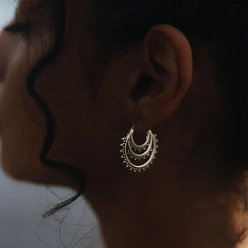 925 sterling silver crescent hoop earrings with layered arcs and granulated bead detailing, worn on a woman's ear.