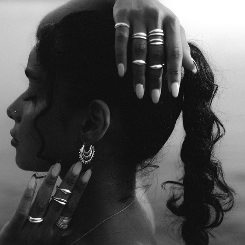 Silver stacking rings paired with a crescent hoop earring, black and white 