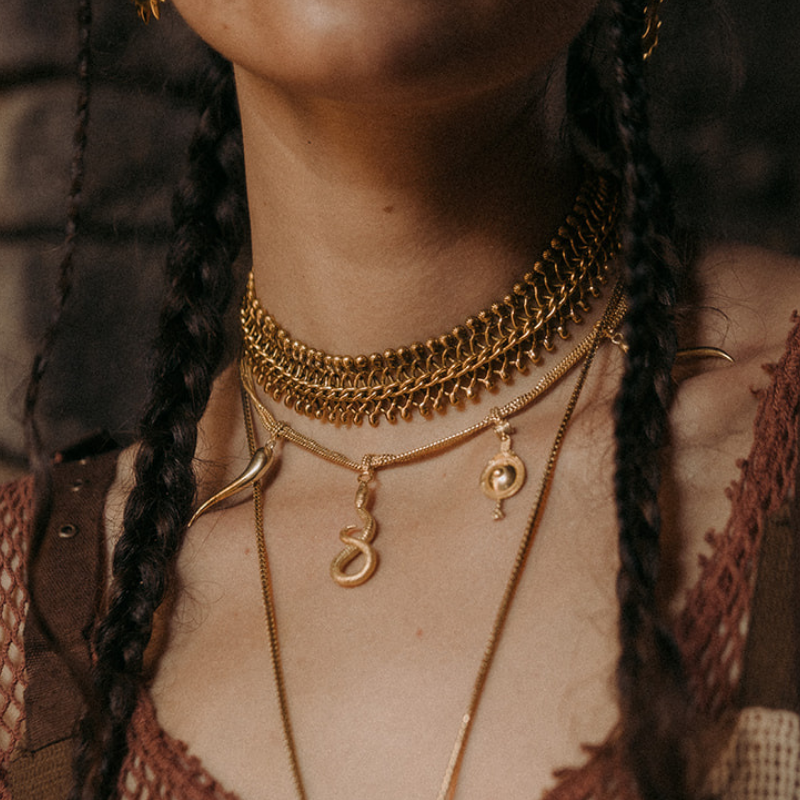 Gold chain choker necklace layered with a snake-shaped pendant charm 