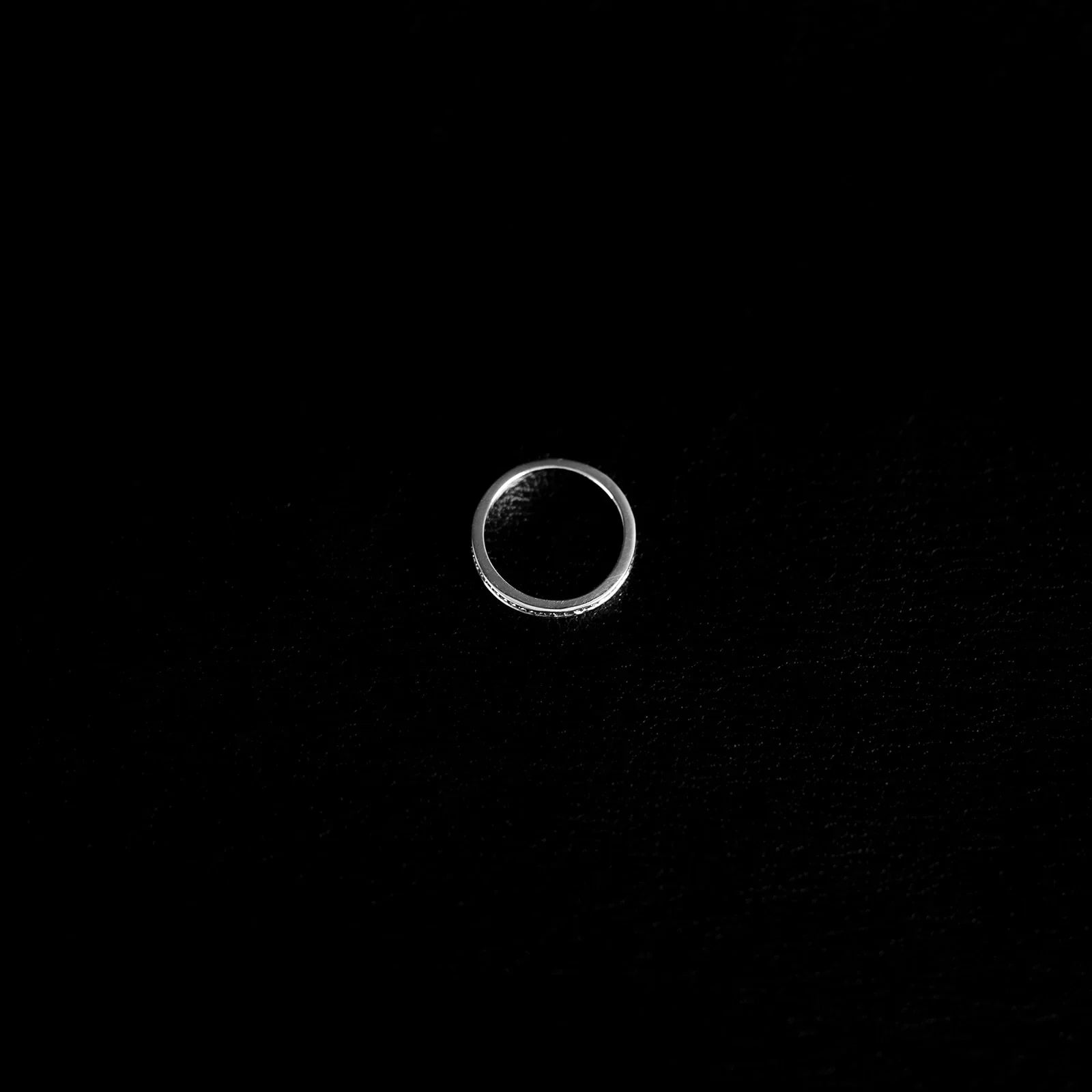 Slender textured 925 sterling silver band ring on a finger, with fine faceted detailing and polished finish.