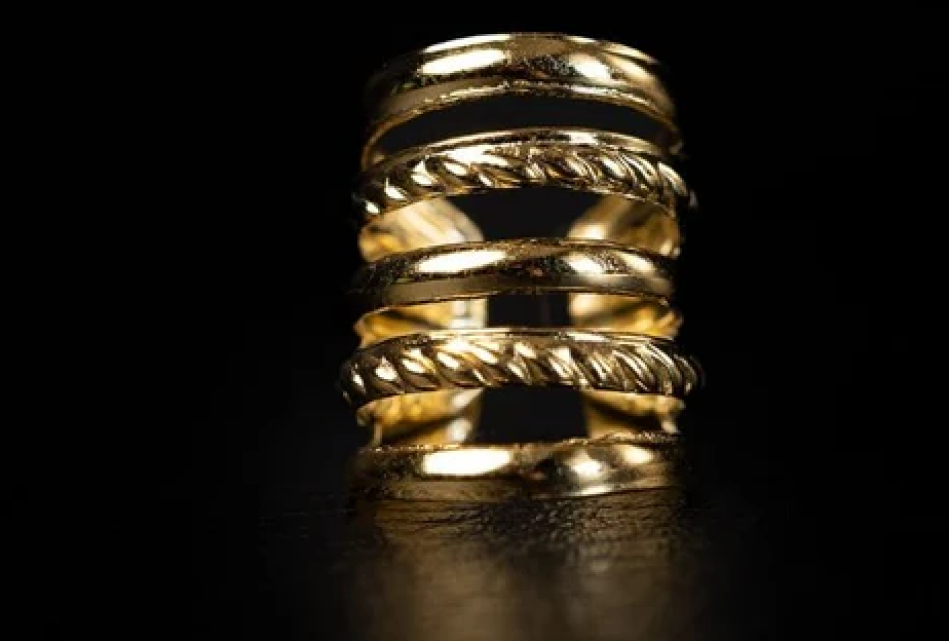 A triple-coil silver ear cuff resting on a dark stone features an open-helix style that requires no piercing.
