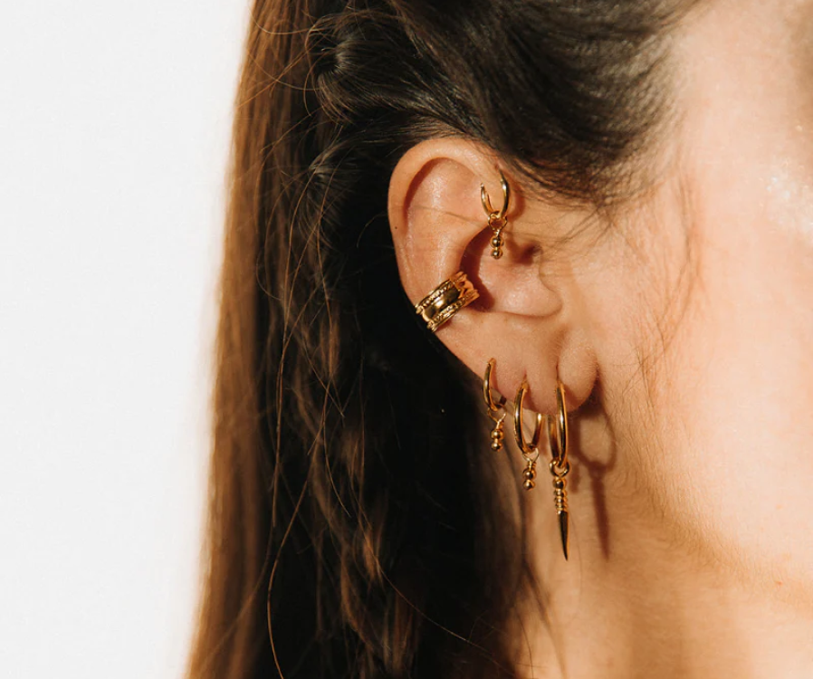 Woman wearing a 22K gold vermeil Devanagari necklace and sun hoops by Noir KĀLA over 925 sterling silver.