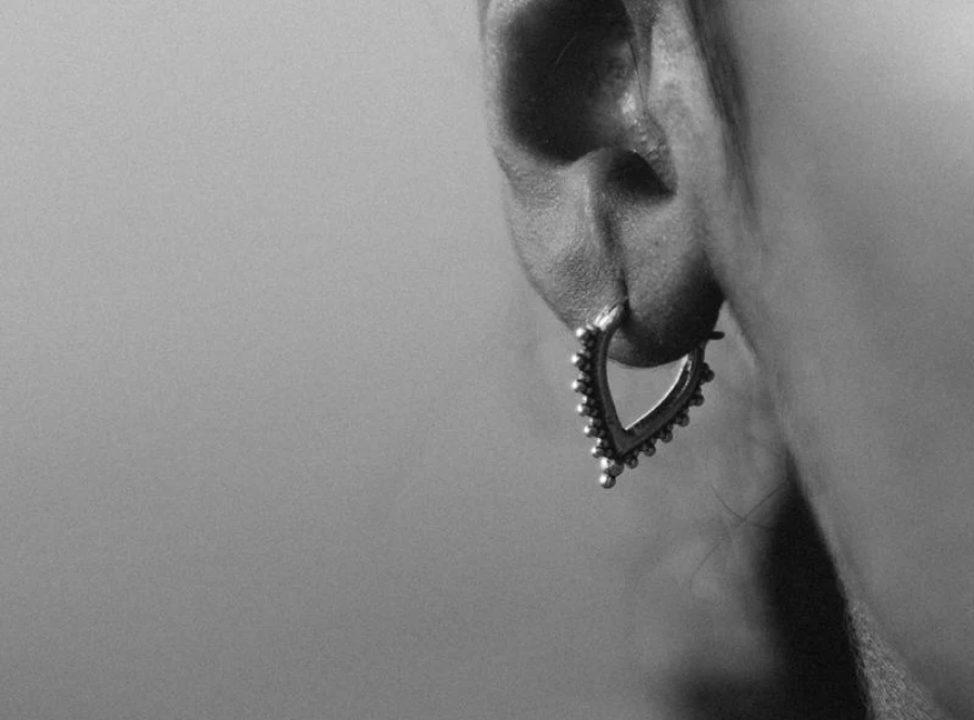 Woman wearing a layered Noir KĀLA ear stack in 22K gold vermeil, showing the depth of finish on handcrafted artisan pieces.